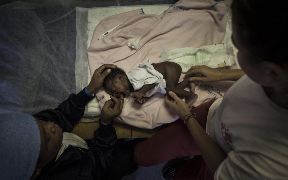 The MSF midwife examines a one-week old baby girl named Salimata, from Ivory Coast, rescued with her mother from an overcrowded rubber dinghy in international waters off Libya. October 10, 2017.