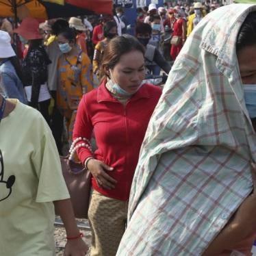 In this March 20, 2020, photo, garment factory workers wear face masks as they walk out at the end of their work shift near Phnom Penh, Cambodia. 