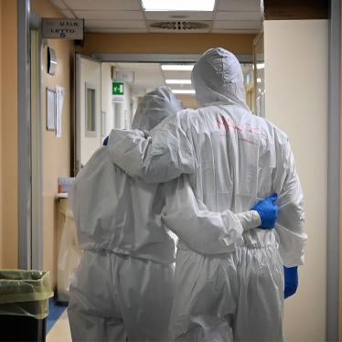 Two medical workers in scrubs embrace in a hospital hallway