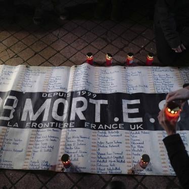 Activists and members of associations defending migrants' rights light candles in front of a banner reading "309 dead on the France UK border since 1999", during a gathering outside the port of Calais, northern France, November 25, 2021. 