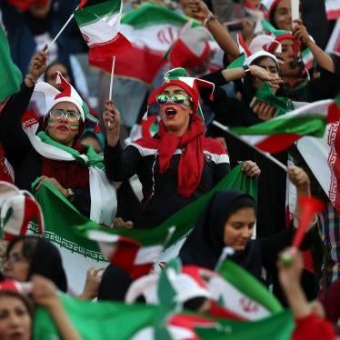 Women cheer holding flags and wearing face paint