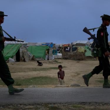 A Rohingya boy watches soldiers patrol his camp