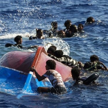Migrants swim next to their overturned wooden boat 
