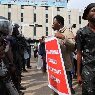 Protester holds sign in front of a line of riot police