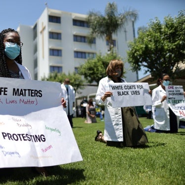 A doctor kneels while holding a sign during a "White Coats for Black Lives" tribute for George Floyd and other African-Americans who died in police custody, outside of a hospital in West Covina, near Los Angeles, California, US, June 11, 2020.