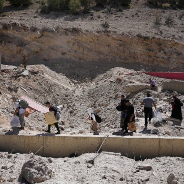 People carry their luggage as they cross into Syria on foot, through a crater caused by Israeli airstrikes aiming to block Beirut-Damascus highway at the Masnaa crossing, in the eastern Bekaa Valley, Lebanon, October 5, 2024.