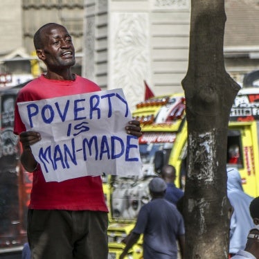 A man holds a poster that reads "poverty is man-made"