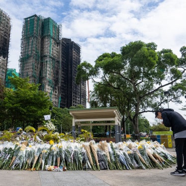 Flower offering in front of burnt buildings, woman praying