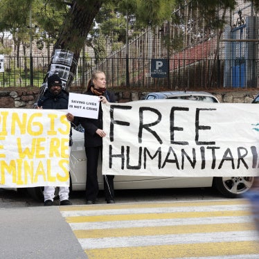 Protesters hold signs outside a Greek court in Mytilene