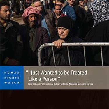 Syrian refugees line up to register or renew their registration at the UNHCR compound in Tripoli, in North Lebanon. A woman stands by a barrier.
