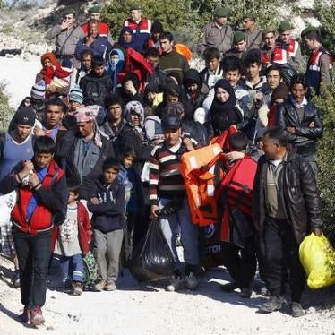 Turkish Gendarmes lead a group of refugees to buses to prevent them from sailing off for the Greek island of Chios by dinghies, at a beach in the western Turkish coastal town of Cesme.