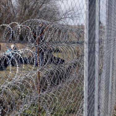 Migrants rest as a policeman watches them near Hungary's border fence on the Serbian side of the border near Morahalom, Hungary, February 22, 2016.