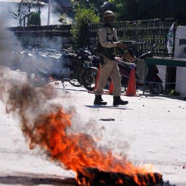 An Indian police officer walks past a burning tire during a protest after Friday prayers in Srinagar, May 25, 2018. REUTERS/Danish Ismail