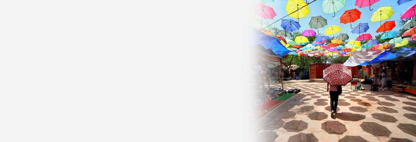 A woman walks with an umbrella in the Dilli Haat open air market in New Delhi, India, April 21, 2023. 